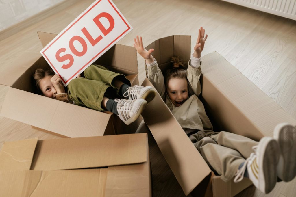 a girl in brown long sleeve shirt and pants lying inside brown cardboard box
